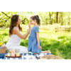 Mother applying sunscreen to her daughter's face at a picnic