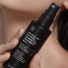 Hand holding Molecular Saviour mist bottle against a model's face