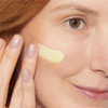 Woman with a swipe of pale yellow retinol serum on her cheek
