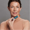 Woman holding the brush-on sunscreen near her face