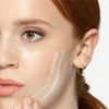 Woman with cleanser streaked on her cheek