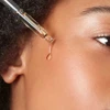Dropper releasing a drop onto a woman's cheek