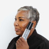 Woman with silver hair holding Pro-Max Age Renewal serum by her cheek