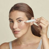 Woman rolling the eye concentrate under her eye