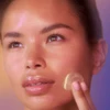 Woman applying a dab of cream to her cheek
