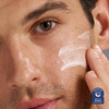 Man smoothing white repair cream onto his cheek