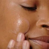 Woman applying Liquid Peelfoliant to her cheek with fingertips