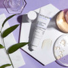 Eye repair tube with leaves and glass dishes on a lavender surface