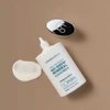 Open No-Show Mineral Sunscreen bottle with cap and a cream swatch on tan background