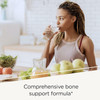 Woman drinking water at a kitchen table with bone support formula text