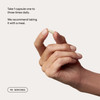 Hand holding a capsule with daily serving directions