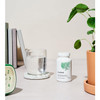 Bottle on a desk beside a glass of water and a plant