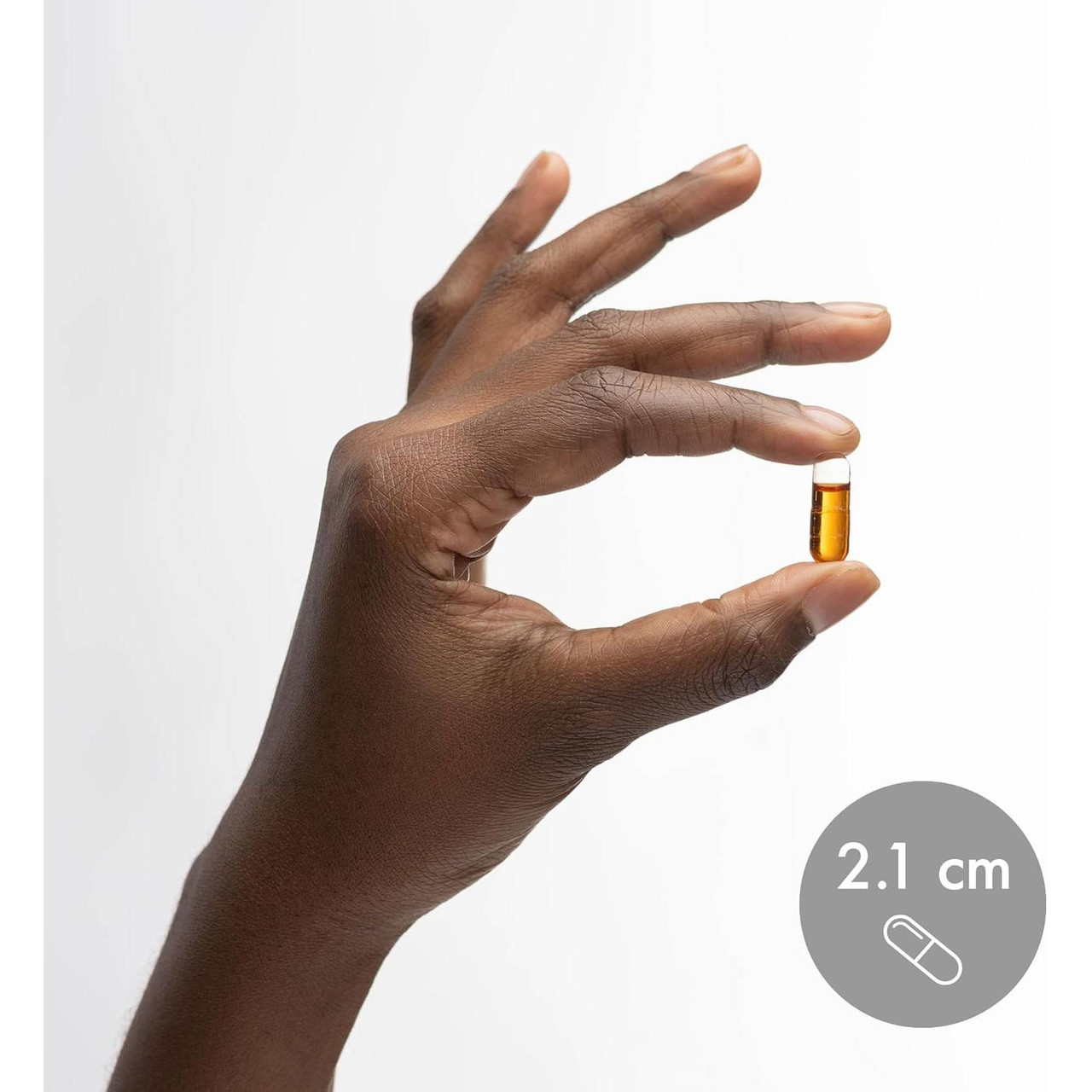 Hand holding a Vitamin E softgel shown at 2.1 cm for size reference