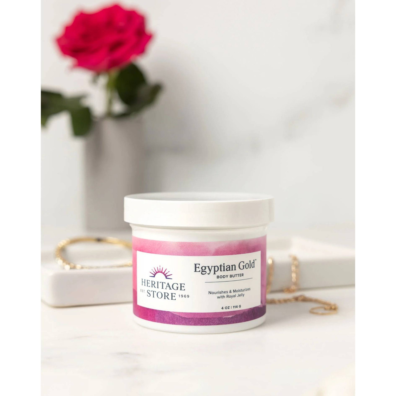 Egyptian Gold Body Butter jar beside a red rose