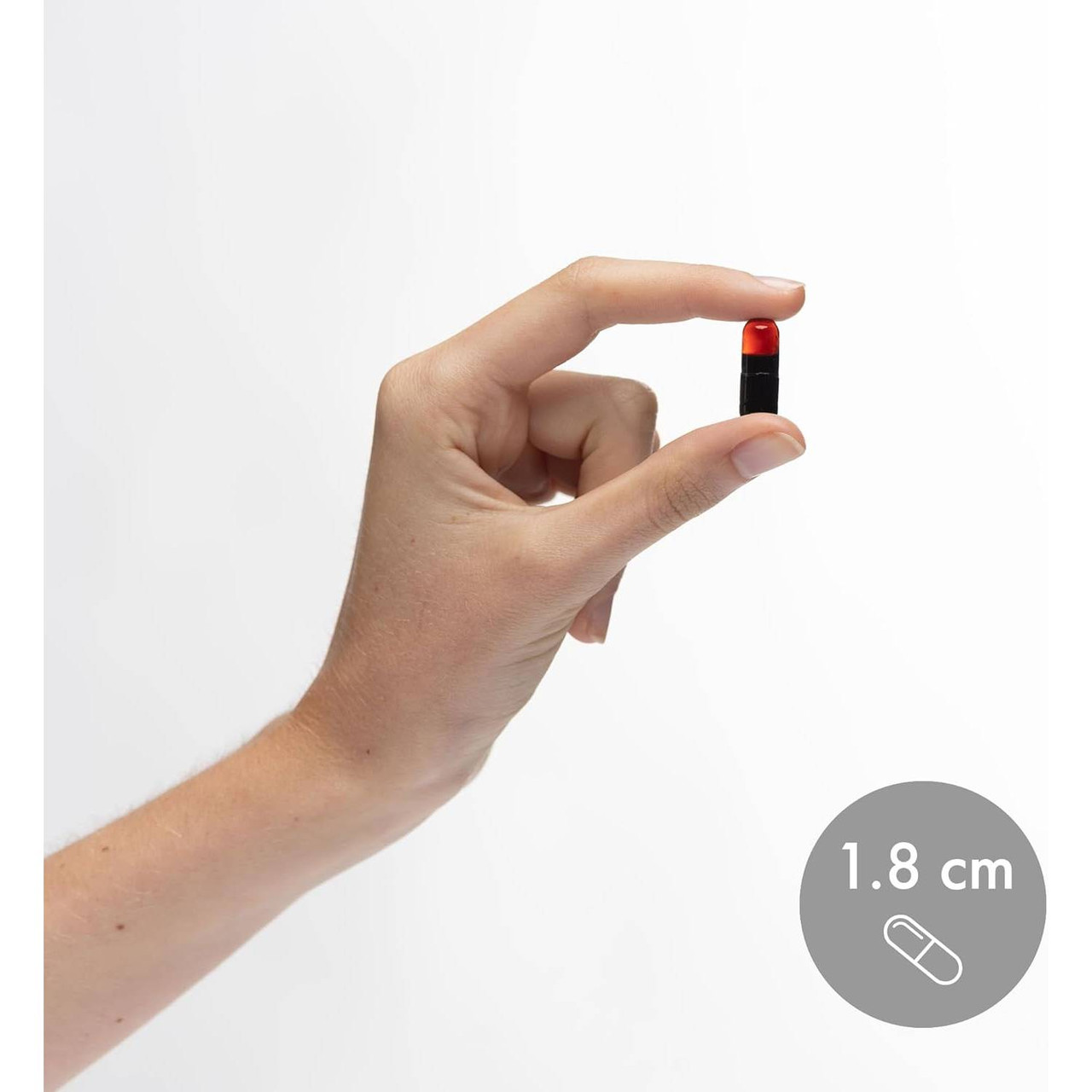 Hand holding an Astaxanthin capsule, 1.8 cm size marker