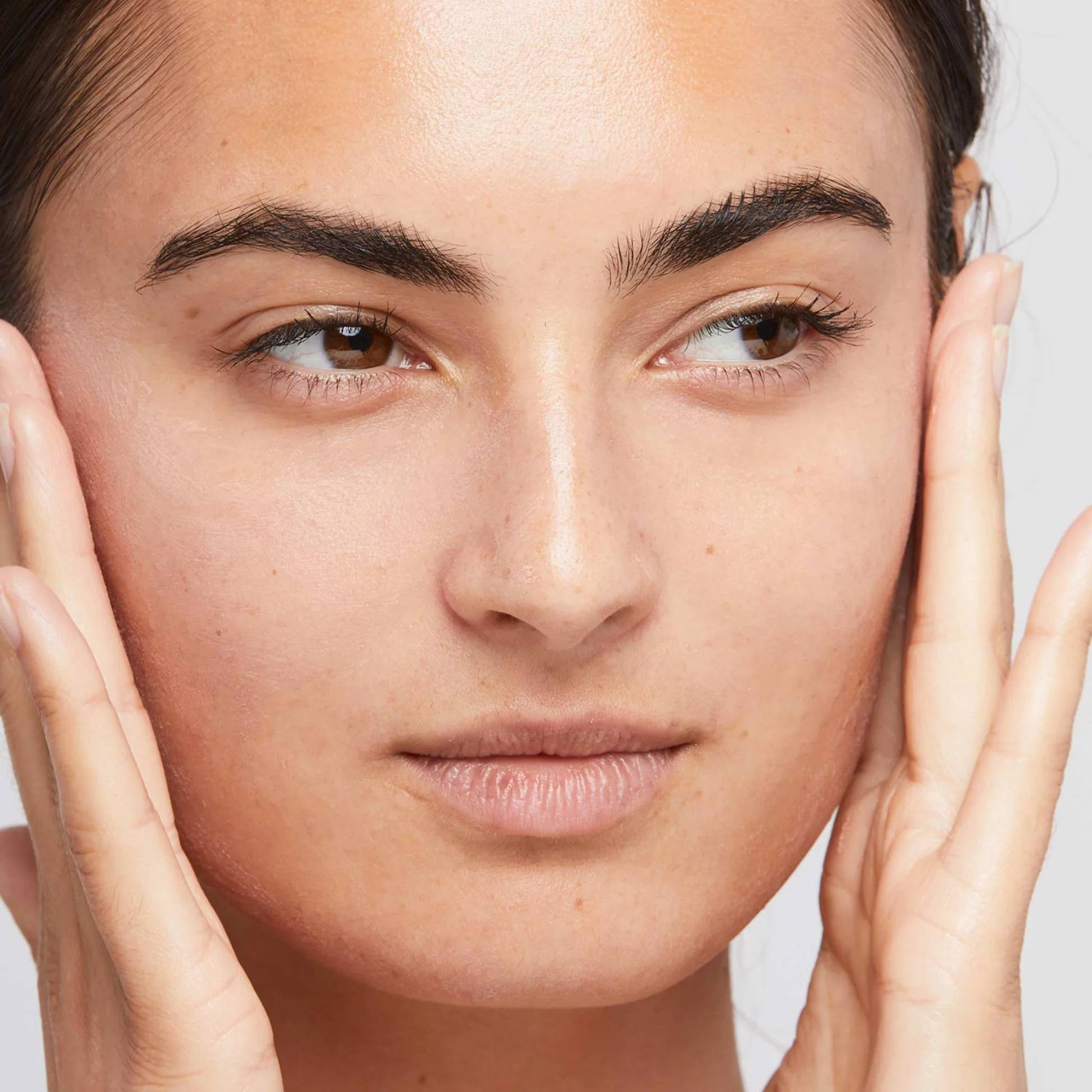 Model touching face with smooth primed skin