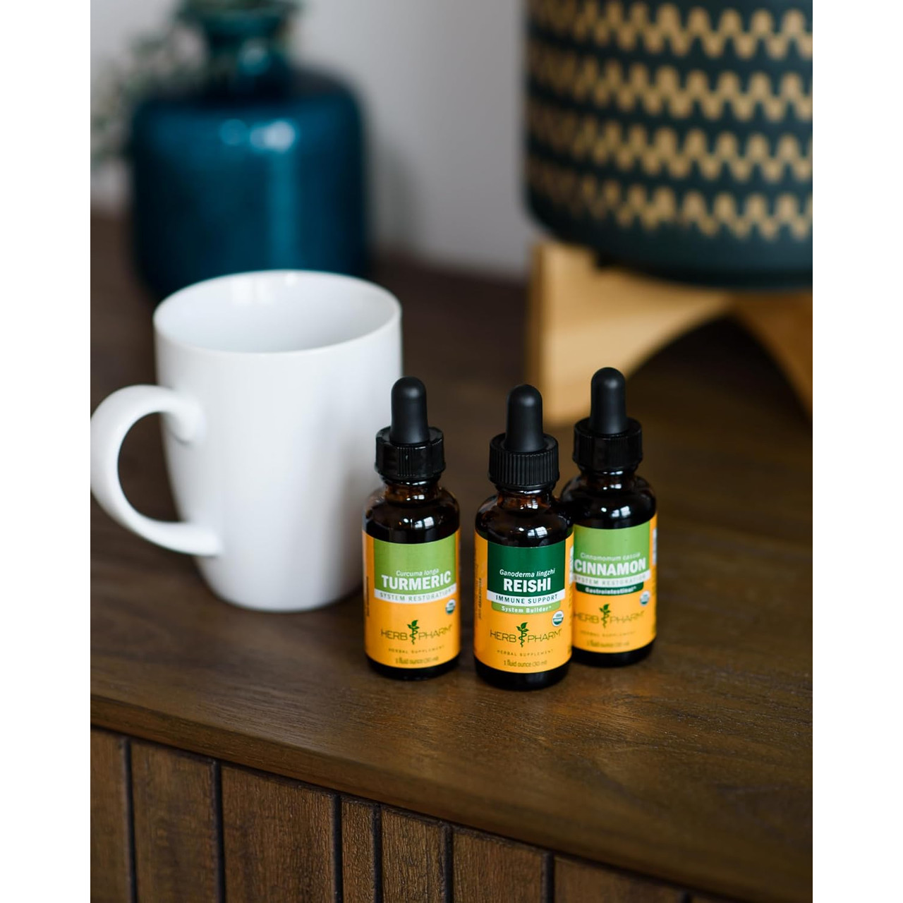 Three Herb Pharm extract bottles beside a white mug on a wooden table