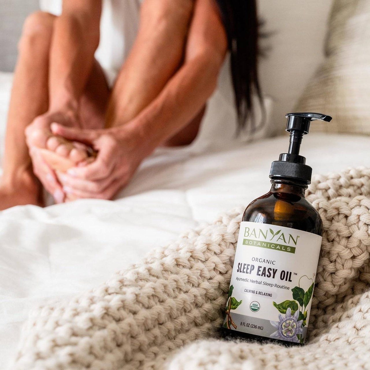 Sleep Easy Oil bottle on a bedside table with feet resting on bed