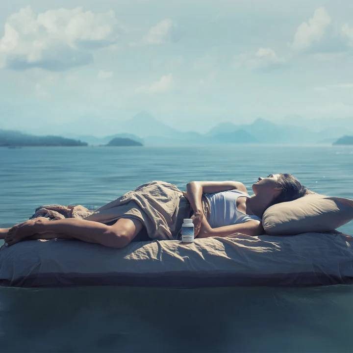 Woman sleeping on a bed by the ocean shoreline lifestyle photo