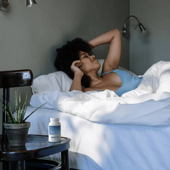 Woman relaxing in bed with ecoSleep bottle on the nightstand