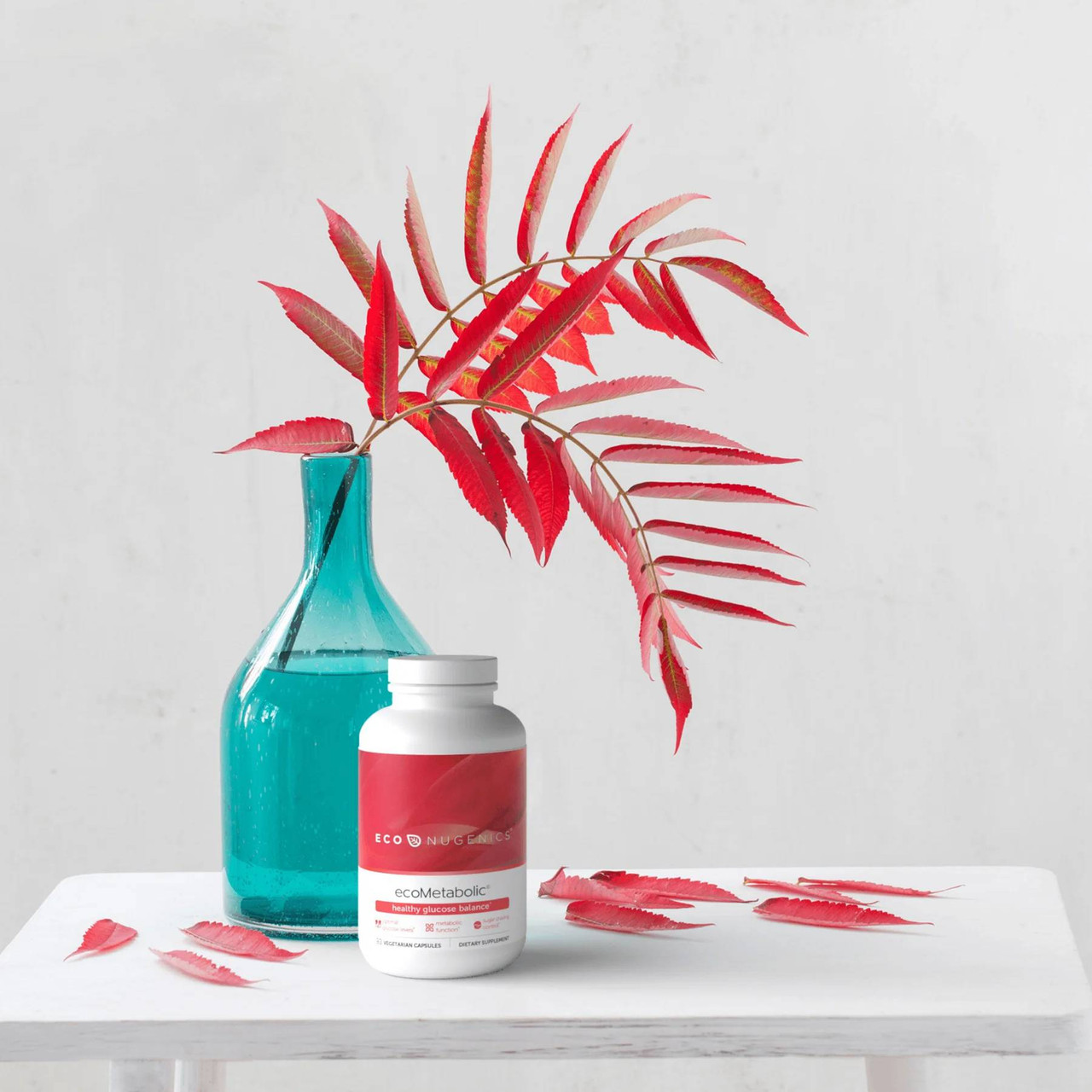 ecoMetabolic bottle beside a teal vase with red leaves