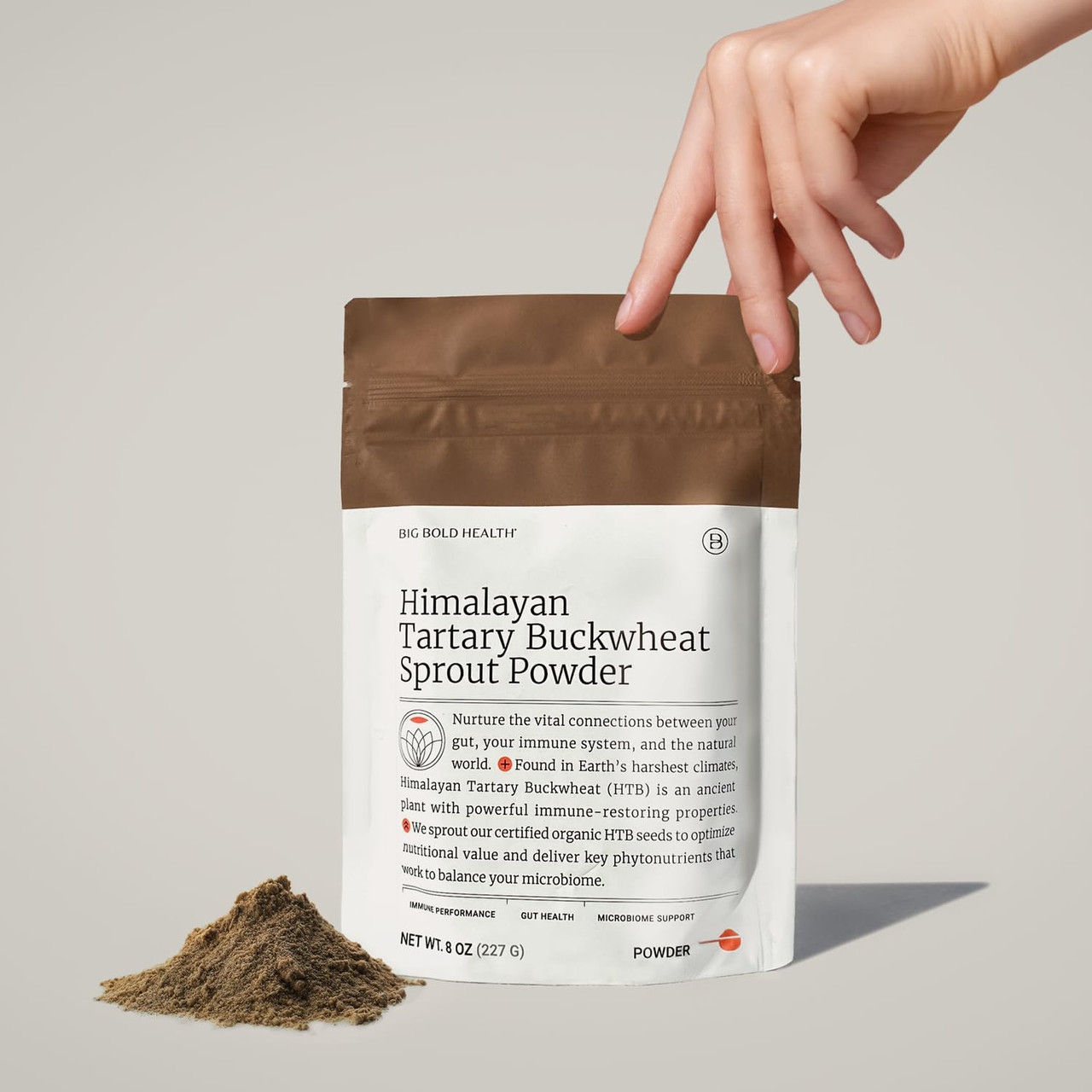 Hand lifting the pouch beside a pile of powder