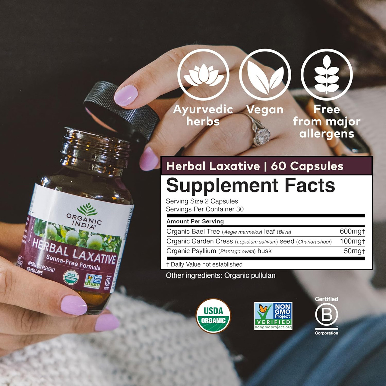 Hand holding Herbal Laxative bottle with supplement facts, Ayurvedic herbs and vegan icons