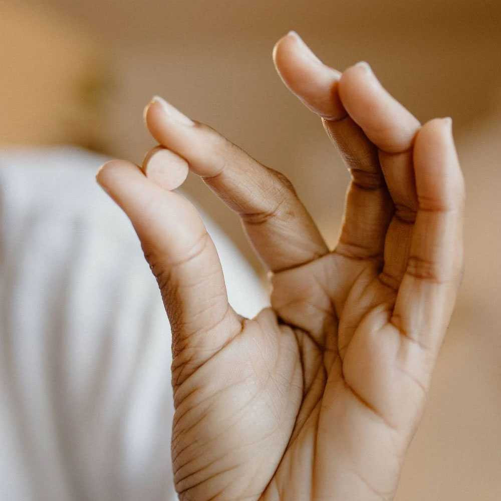 Fingers holding a single tablet
