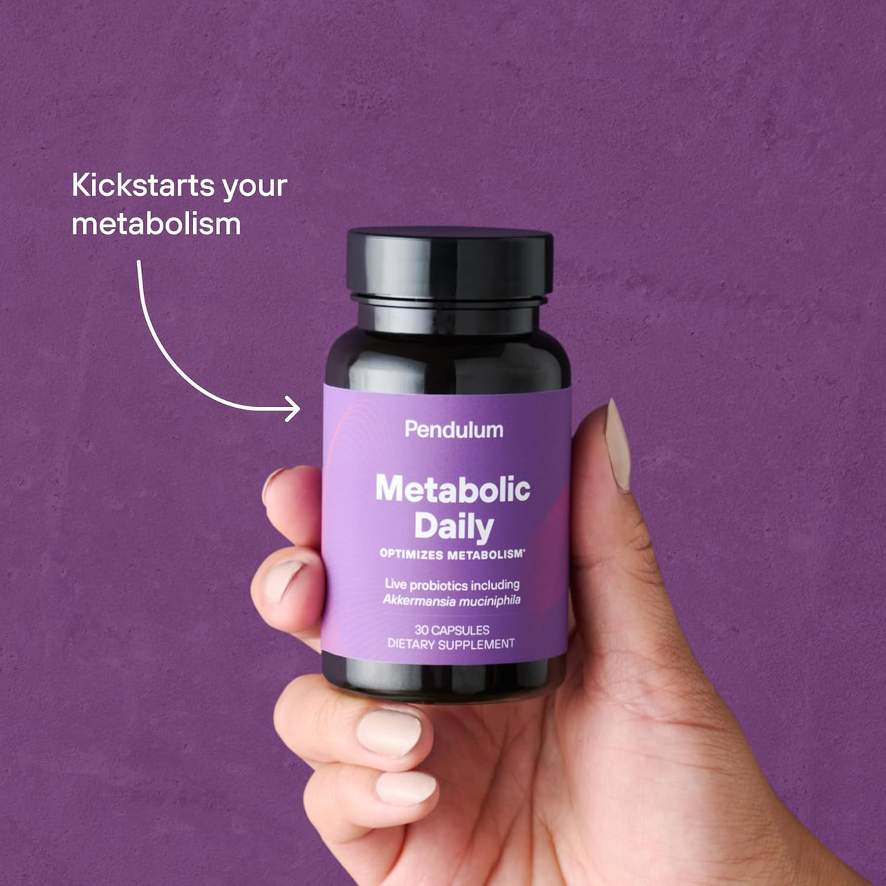 Hand holding the Metabolic Daily bottle on a purple background