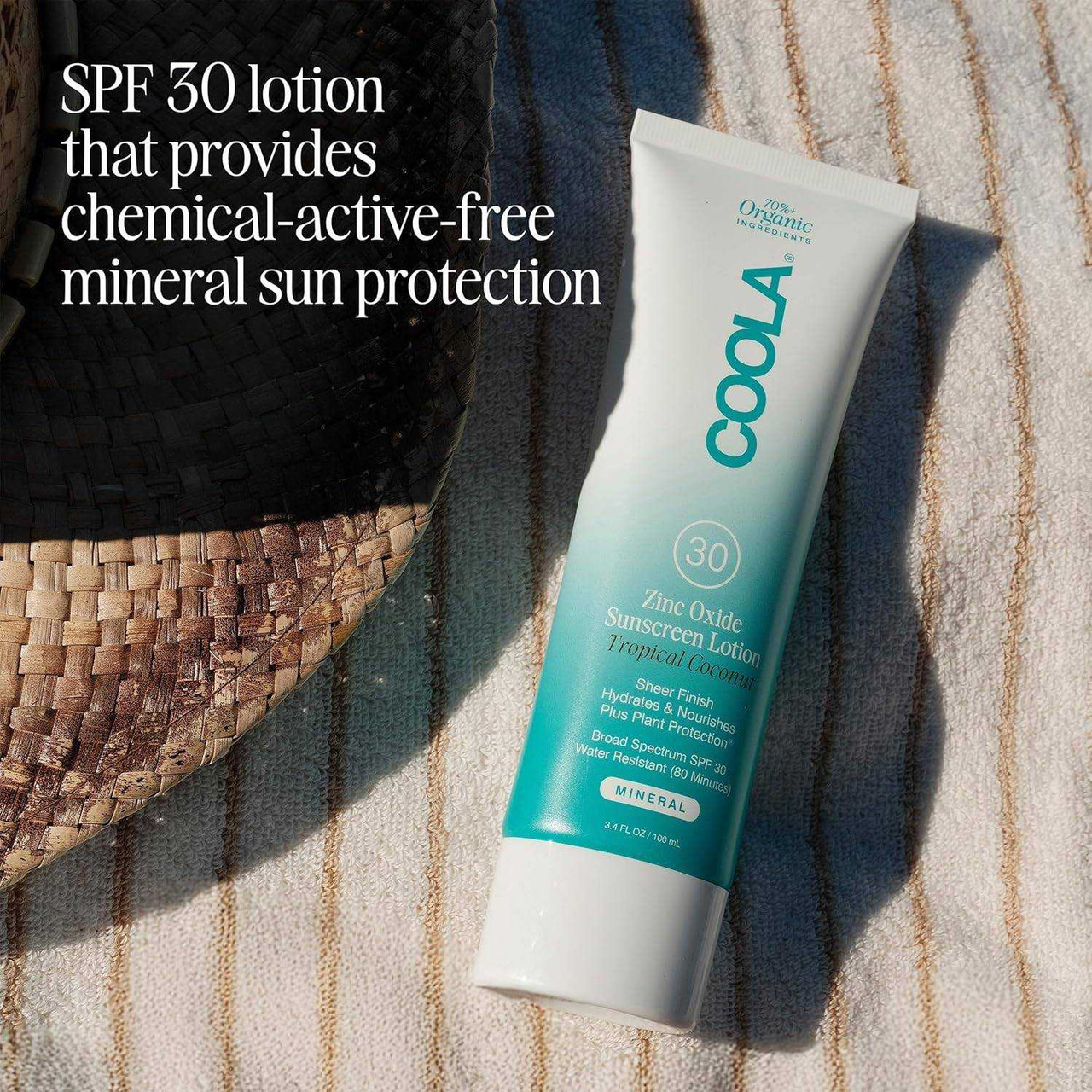 Coola Mineral Body Lotion SPF 30 tube on a striped towel, chemical-active-free mineral sun protection