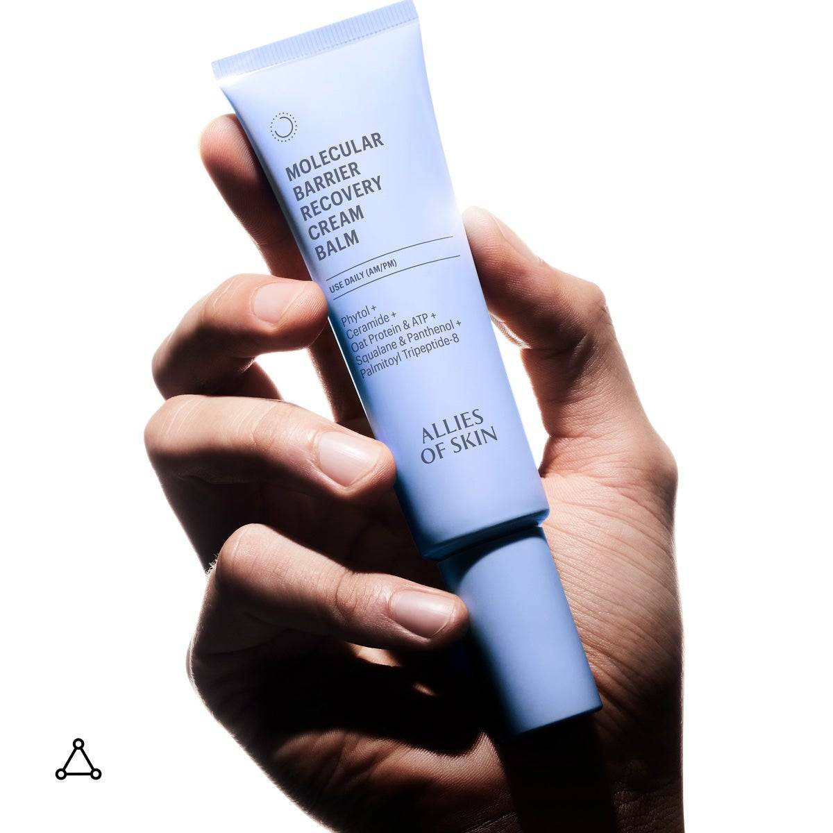 Hand holding the Molecular Barrier Recovery Cream Balm tube