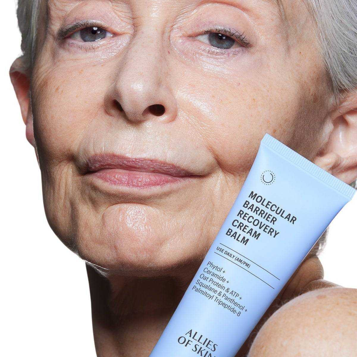 Older woman holding the cream balm tube against her cheek