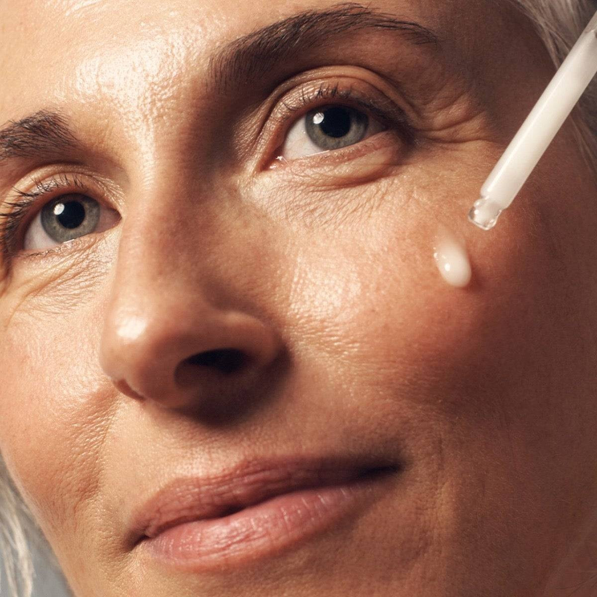 Dropper applying dose of wisdom serum to cheek