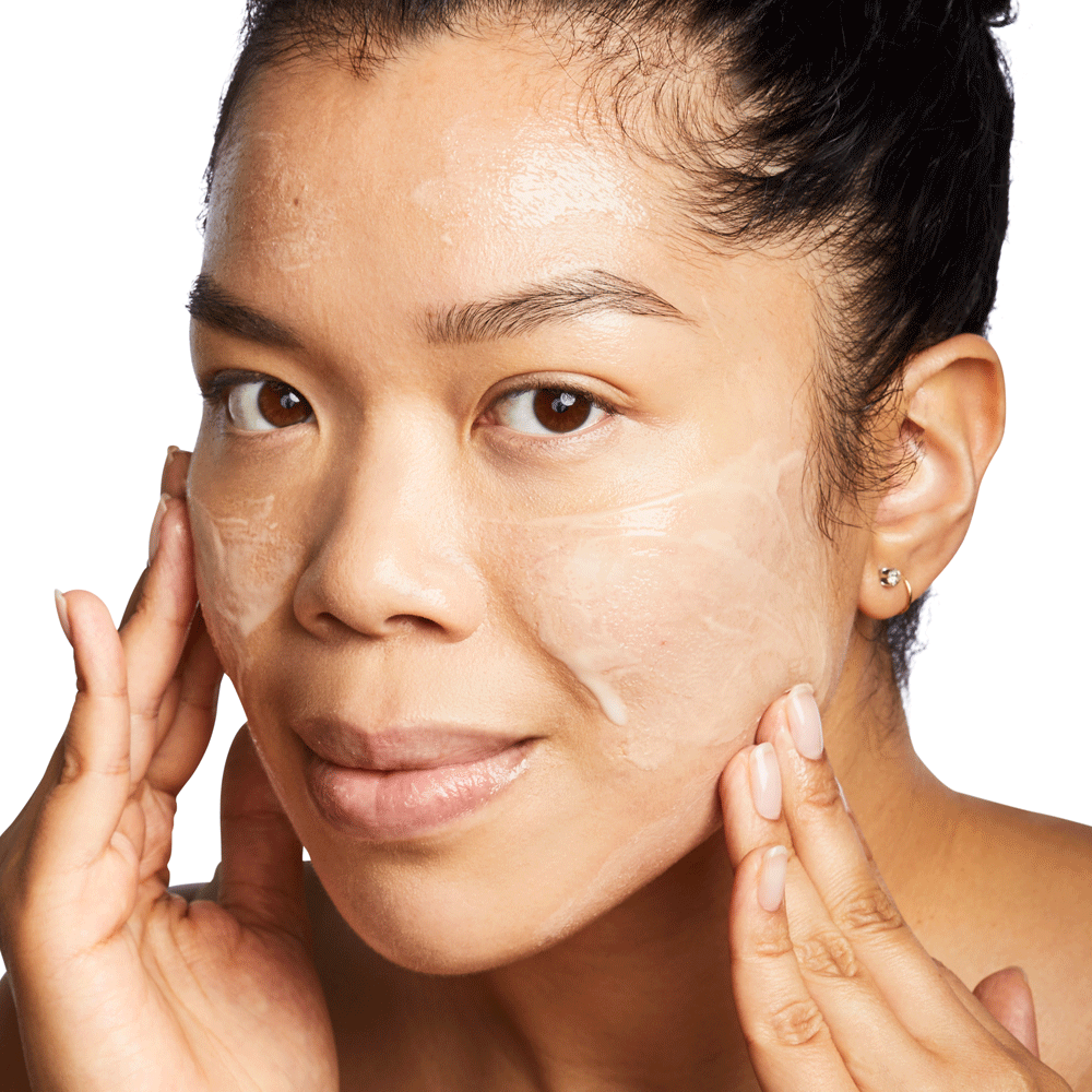 Woman massaging foamy cleanser onto her cheeks