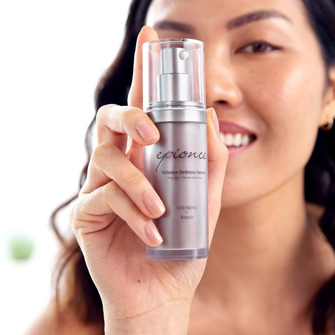 Smiling model holding epionce Intense Defense Serum bottle