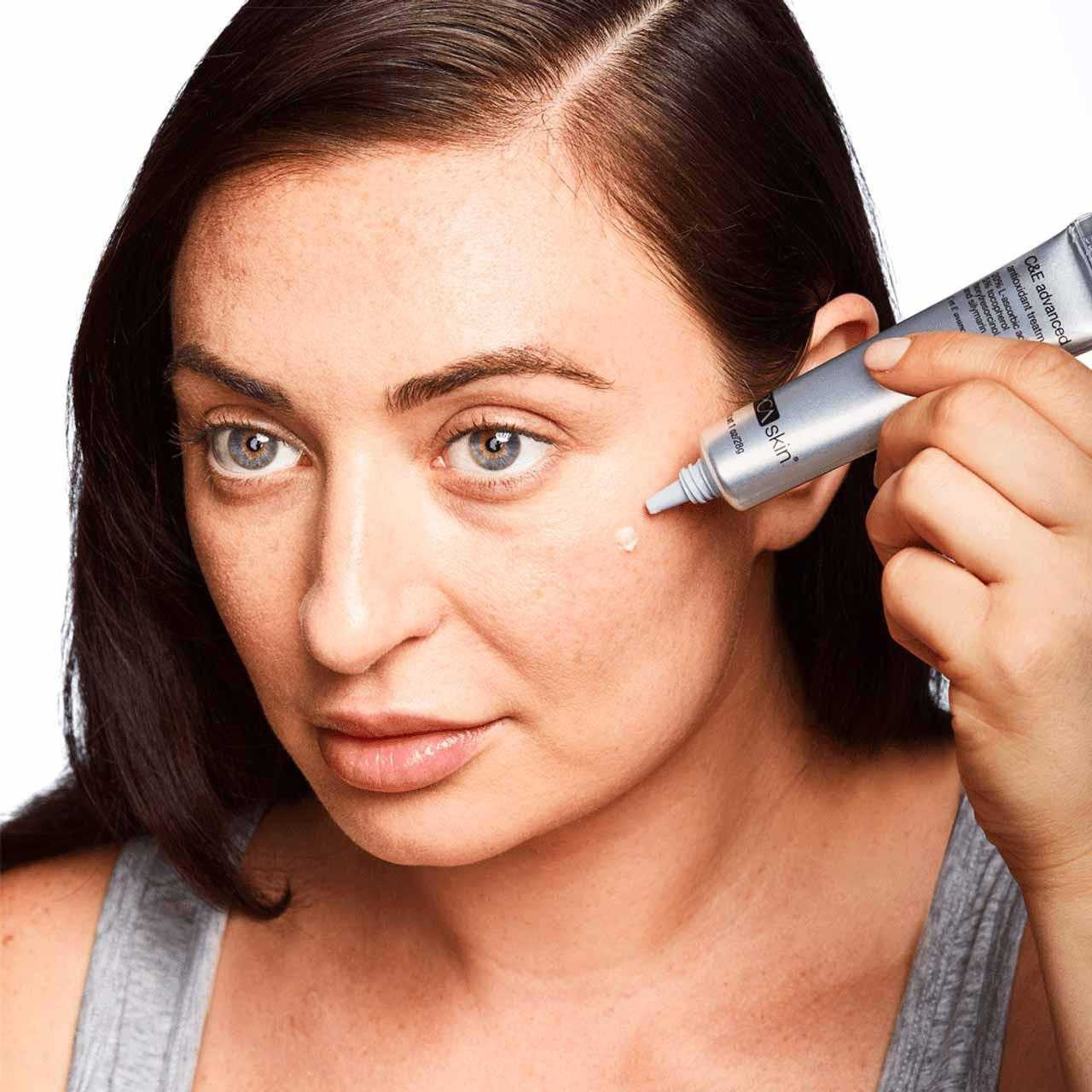 Woman applying PCA Skin C&E Advanced from the tube to her cheekbone