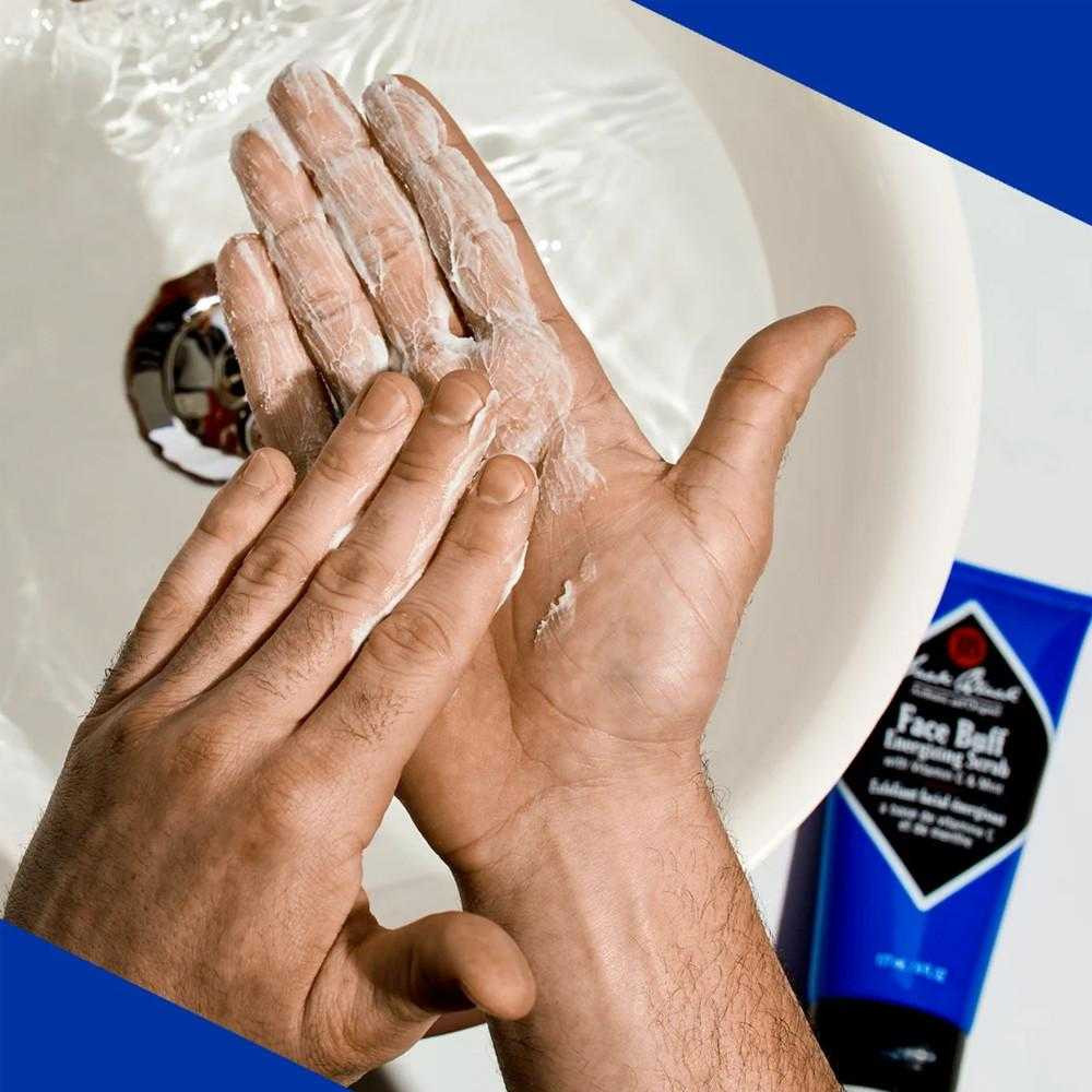 Man lathering scrub between his hands over a sink beside Face Buff tube