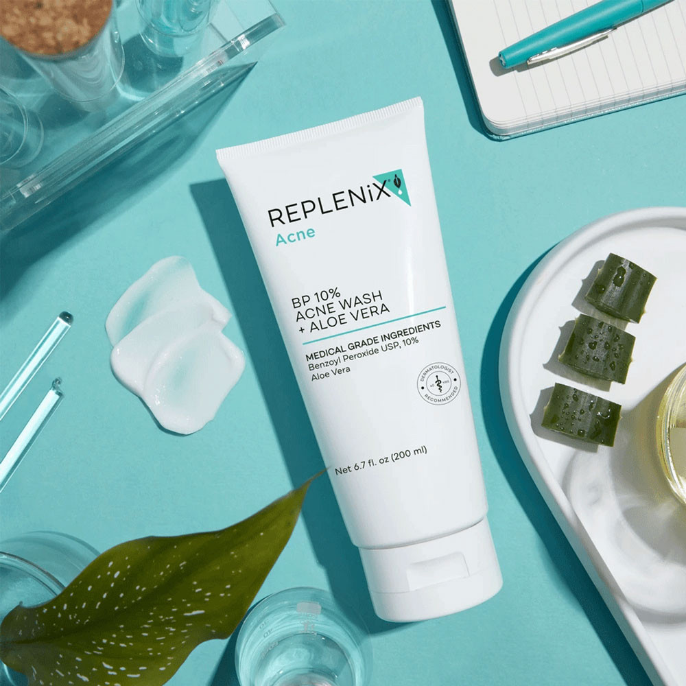 Acne wash tube on a teal surface with aloe pieces