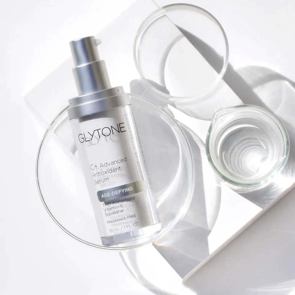 Glytone C+ serum bottle among clear glass dishes