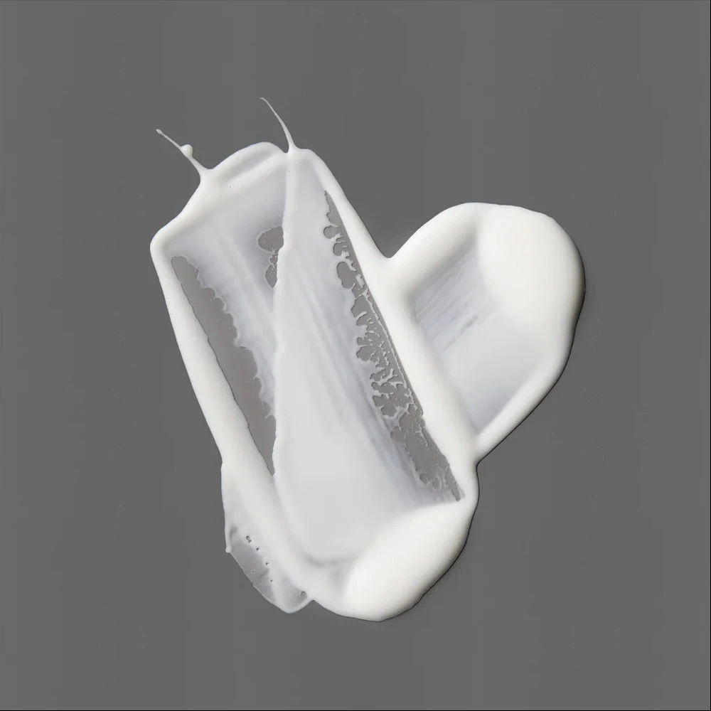 Swipes of white serum on a gray background