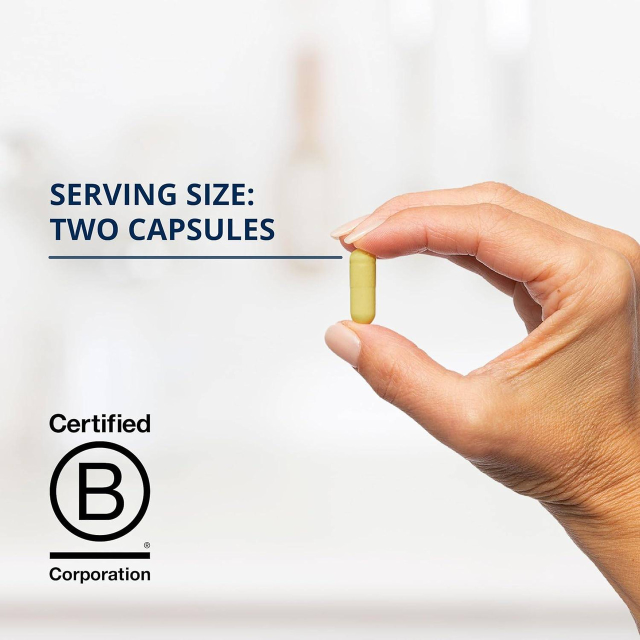 Hand holding a yellow capsule, serving size two capsules
