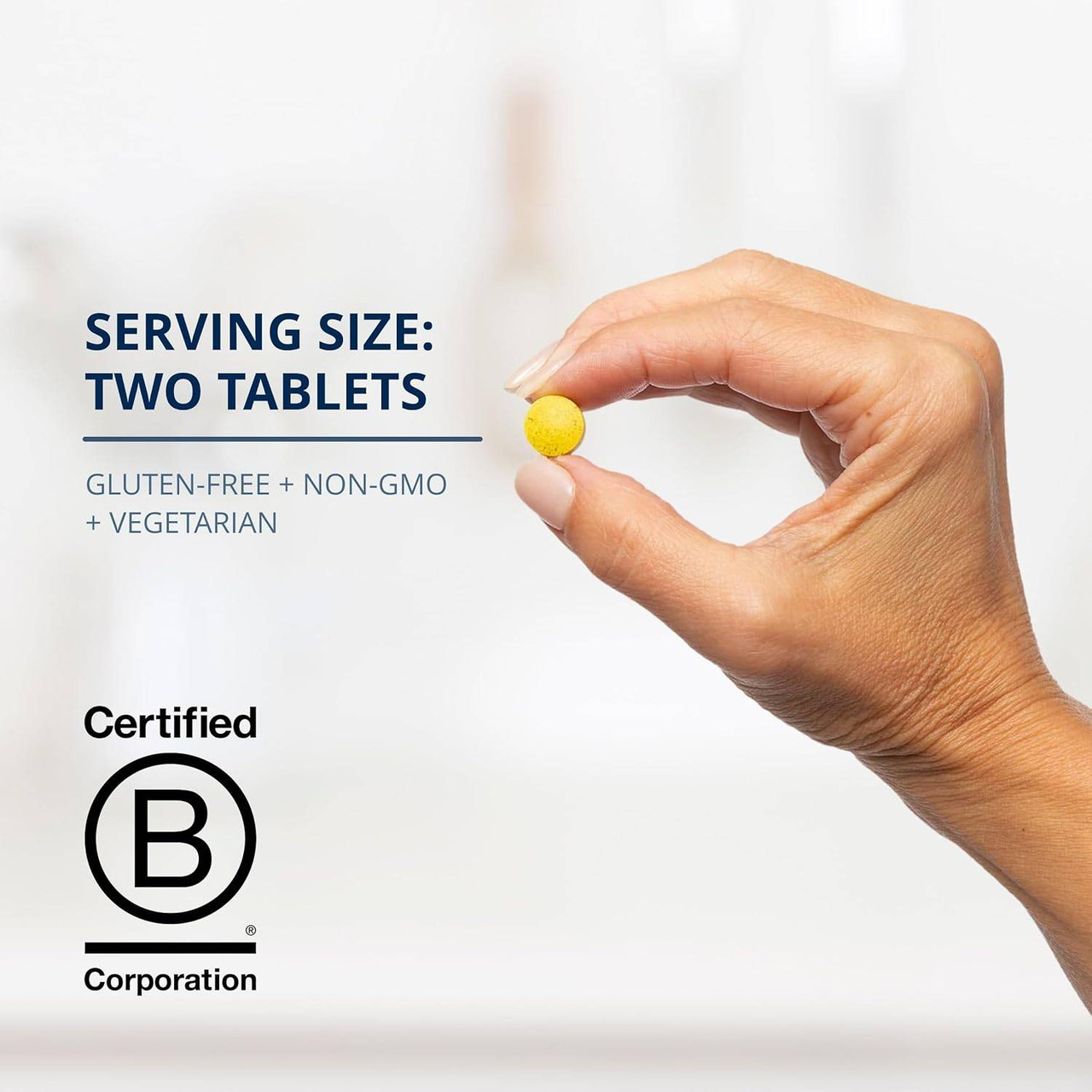 Hand holding a yellow tablet, serving size two tablets