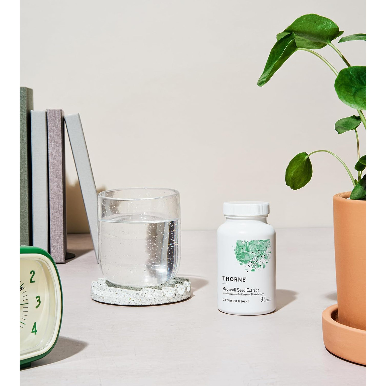 Bottle on a desk beside a glass of water and a plant