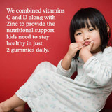 Young girl eating a gummy, vitamins C and D with zinc graphic