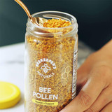 Hand scooping bee pollen from an open jar