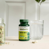 Gotu Kola bottle beside a glass of water and a jar of herbs