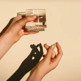 Hands holding a glass of water casting a shadow
