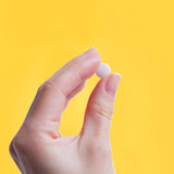 Hand holding a white Mood Bites chewable against yellow background