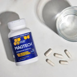 MagTech bottle with capsules beside a glass of water