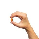 Hand holding an orange softgel